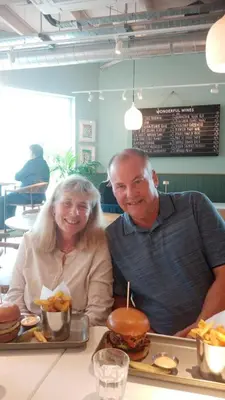 a man and woman sitting at a table with a hamburger at Comfortable room with en suite in Edinburgh