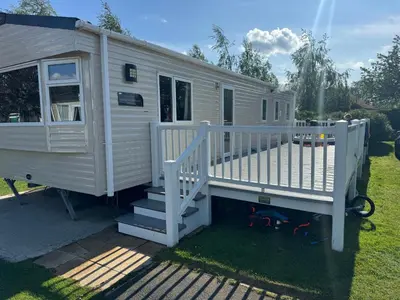 a white tiny house with a porch and stairs at Tattershall caravan with private hot tub in Moffat
