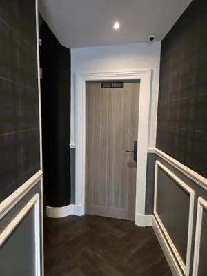 a hallway with a door with a exit sign on it at Stlll Brae Apartment in Tarbet
