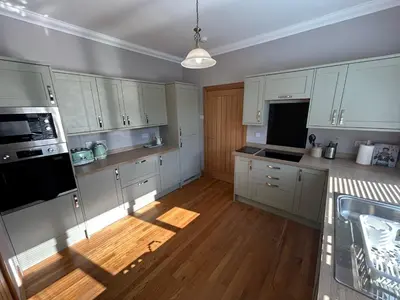 a kitchen with white cabinets and a wooden floor at Shawsmill, outside Hurlford in Hurlford