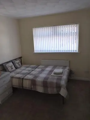 a bedroom with a bed with a plaid blanket and a window at Studio Twenty One in Whitburn