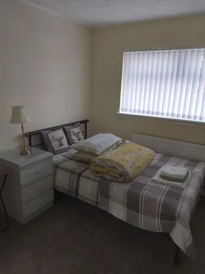 a bedroom with a bed and a dresser and a window at Studio Twenty One in Whitburn