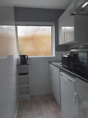 a small kitchen with a microwave and a window at Studio Twenty One in Whitburn