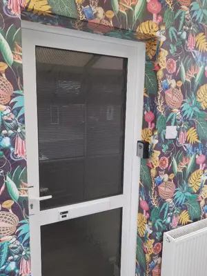 a door in a wall with a tropical wallpaper at Studio Twenty One in Whitburn