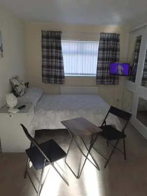 a bedroom with a bed and two chairs and a table at Studio Twenty One in Whitburn
