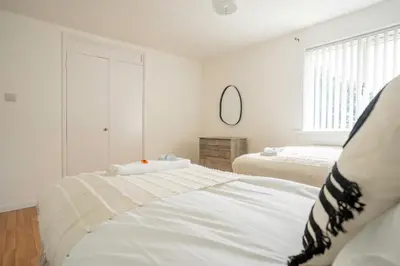 a white bedroom with two beds and a mirror at 4 BDR House By Caledonia Luxe Stays Short Lets & Serviced Accommodation Livingston in Livingston
