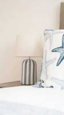 a bedside table with a lamp and a pillow at 4 BDR House By Caledonia Luxe Stays Short Lets & Serviced Accommodation Livingston in Livingston