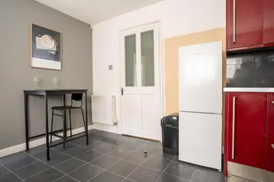 a kitchen with a table and a white refrigerator at 4 BDR House By Caledonia Luxe Stays Short Lets & Serviced Accommodation Livingston in Livingston