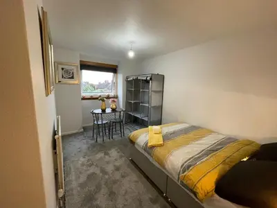 a bedroom with a bed and a table in it at Vibrant Room in Centeral Ayr in Ayr
