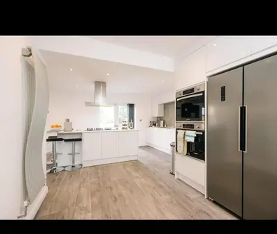 a large kitchen with white cabinets and stainless steel appliances at Asentral Homes in Moffat
