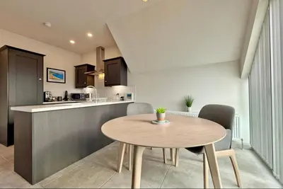 a kitchen and dining room with a wooden table and chairs at Stylish apartment in Portstewart in Moffat