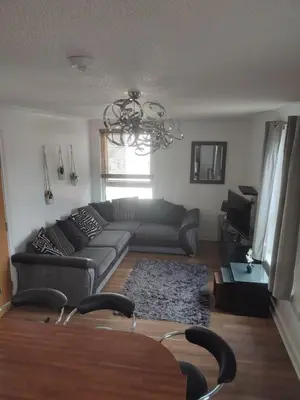 a living room with a black couch and a chandelier at Rosebank Apartment Edinburgh City in Edinburgh