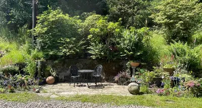 a patio with two chairs and a table in a garden at Craigielands House in Beattock