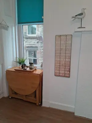 a room with a wooden table and a window at The Port in Port Bannatyne