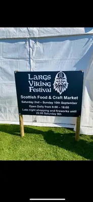 a sign in the grass in front of a tent at Largs Sandringham Apartment in Largs