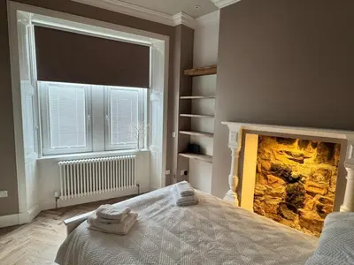 a bedroom with a fireplace with towels on a bed at Largs Sandringham Apartment in Largs