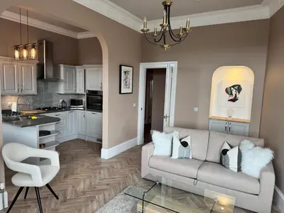 a living room with a couch and a kitchen at Largs Sandringham Apartment in Largs