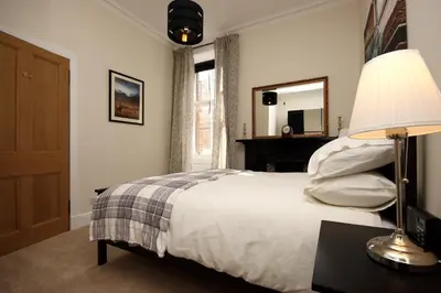 a bedroom with a bed with a lamp and a mirror at Hamish's Hame Edinburgh Licence No EH 69774 R Energy Rating C in Edinburgh