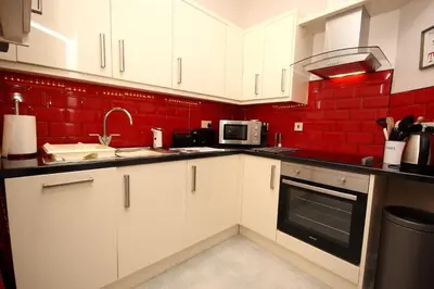 a kitchen with white cabinets and a red wall at Hamish's Hame Edinburgh Licence No EH 69774 R Energy Rating C in Edinburgh