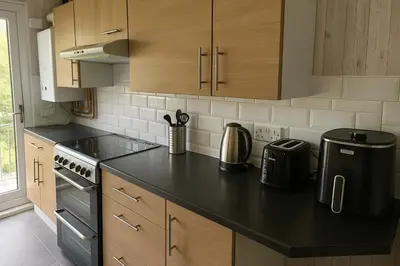 a kitchen with wooden cabinets and a black counter top at Cozy 2BR Flat Near City Centre Free Parking Fast Wifi in Edinburgh