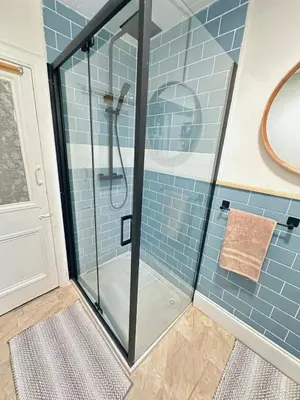 a shower in a bathroom with blue tiles at Duplex - City Centre 4-Bed Retreat in Edinburgh