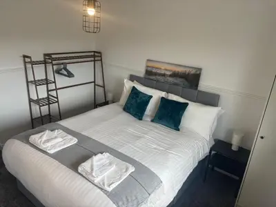 a bedroom with a bed with white sheets and blue pillows at NEW - 3 Bedroom House in East Kilbride in East Kilbride