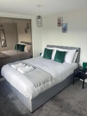 a bedroom with a large bed with green and white pillows at NEW - 3 Bedroom House in East Kilbride in East Kilbride