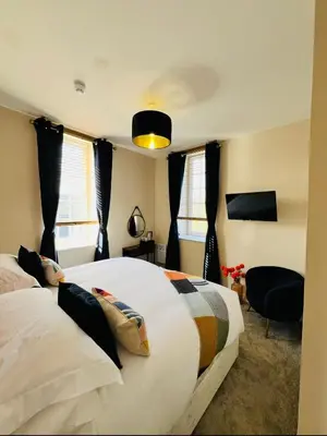 a bedroom with two white beds and a chair at The courtyard bar, kitchen, rooms in Falkirk