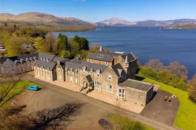 an aerial view of a large house on a lake at Stunning Flat in Loch Lomond in Luss