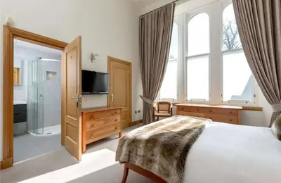 a bedroom with a large bed and a television at Stunning Flat in Loch Lomond in Luss
