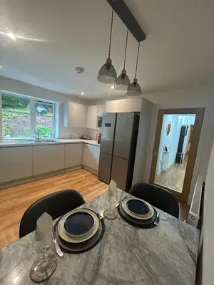 a dining room table with chairs and a kitchen at The West Wing - 1Bedroom Annexe with parking in Oban