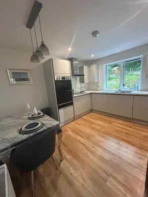 a large kitchen with a wooden floor and a table at The West Wing - 1Bedroom Annexe with parking in Oban