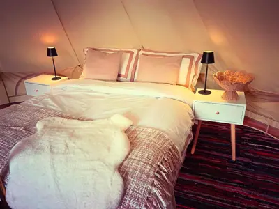 a bedroom with a large bed with two tables and two lamps at Infinite Sky camping in Moffat