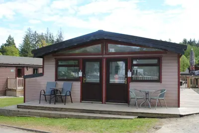 a small cabin with chairs and a table on a deck at Rowardennan Rooms in the lodge Lodge no 2 in Rowardennan