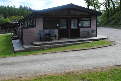 a small cabin with tables and chairs on the porch at Rowardennan Rooms in the lodge Lodge no 2 in Rowardennan