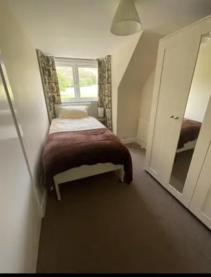 a small bedroom with a bed and a mirror at Wood Cottage in Peebles