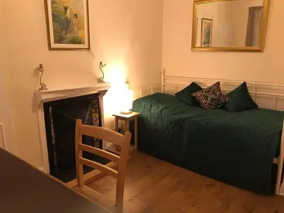 a bedroom with a bed and a chair and a fireplace at Wood Cottage in Peebles