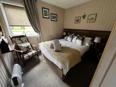 a bedroom with a large bed and a chair at Breacan Lodge in Hunters Quay