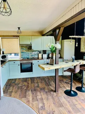 a kitchen with white cabinets and a wooden floor at Breacan Lodge in Hunters Quay
