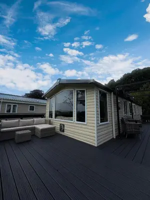 a house with a deck with a couch on it at Moselle - 6 Squirrel View in Ballantrae