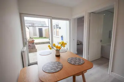 a dining room with a table with flowers on it at Modern 2Bed Garden Apartment in Heart of Penarth in Moffat