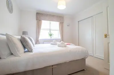 a bedroom with a large white bed with a window at The Well - 3 bedroom apartment in Motherwell