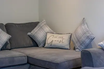 a couch with a pillow that says let one guest at The Well - 3 bedroom apartment in Motherwell