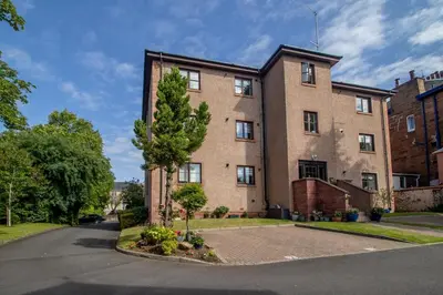 a large brick building with a tree in front of it at The Well - 3 bedroom apartment in Motherwell