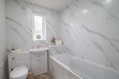 a white bathroom with a tub and a toilet and a sink at Leven Loft - 2 Bed Flat in Coatbridge in Coatbridge