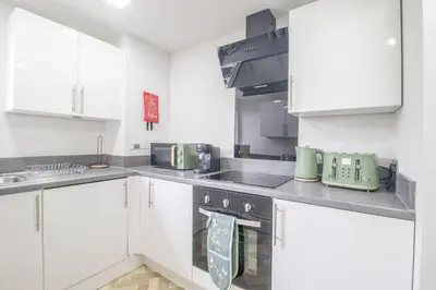 a kitchen with white cabinets and green appliances at Leven Loft - 2 Bed Flat in Coatbridge in Coatbridge