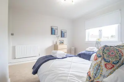 a white bedroom with two beds and a window at Leven Loft - 2 Bed Flat in Coatbridge in Coatbridge