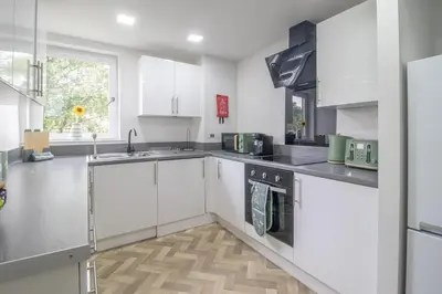 a white kitchen with white cabinets and a sink at Leven Loft - 2 Bed Flat in Coatbridge in Coatbridge
