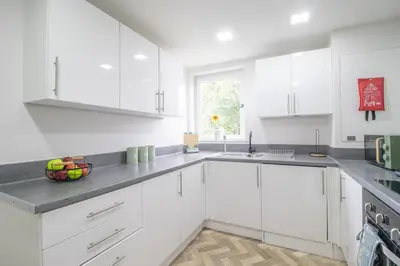 a white kitchen with white cabinets and a window at Leven Loft - 2 Bed Flat in Coatbridge in Coatbridge