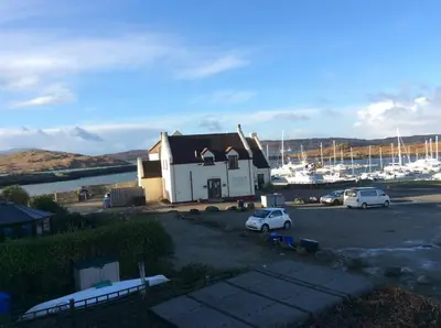 a building with two cars parked in a parking lot at Morvern Cottage in Craobh Haven